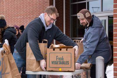 Volunteers with Cuyahoga County Public Library and Greater Cleveland Food Bank sory and box food for distribution.